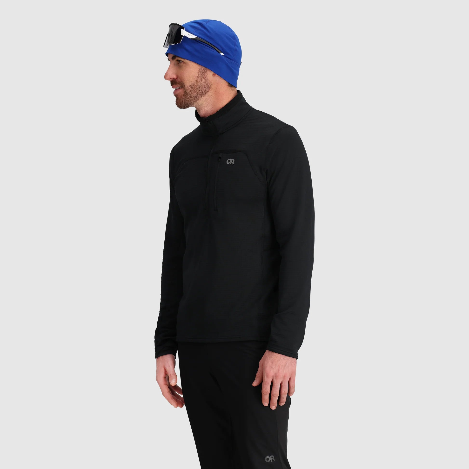 Man wearing a black long-sleeve shirt and blue beanie on a light gray background