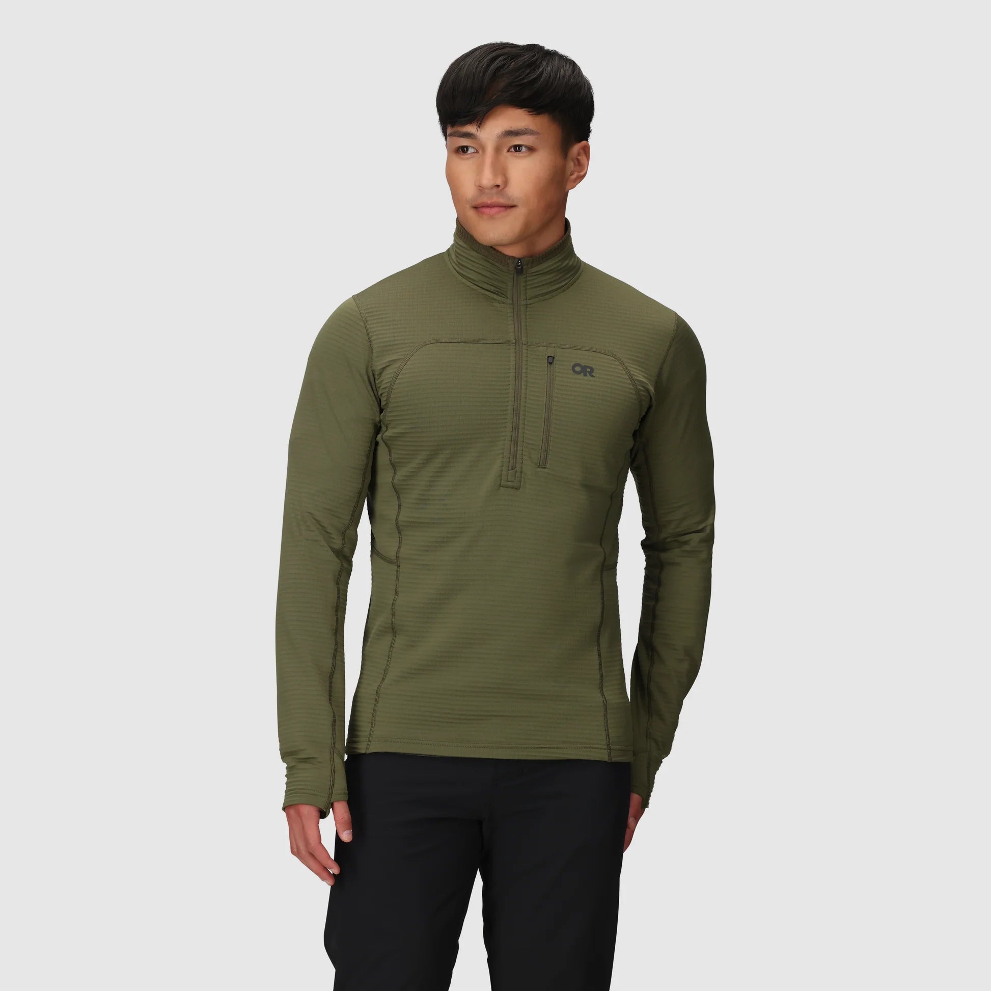 Person wearing a green pullover with a brand logo on a gray background