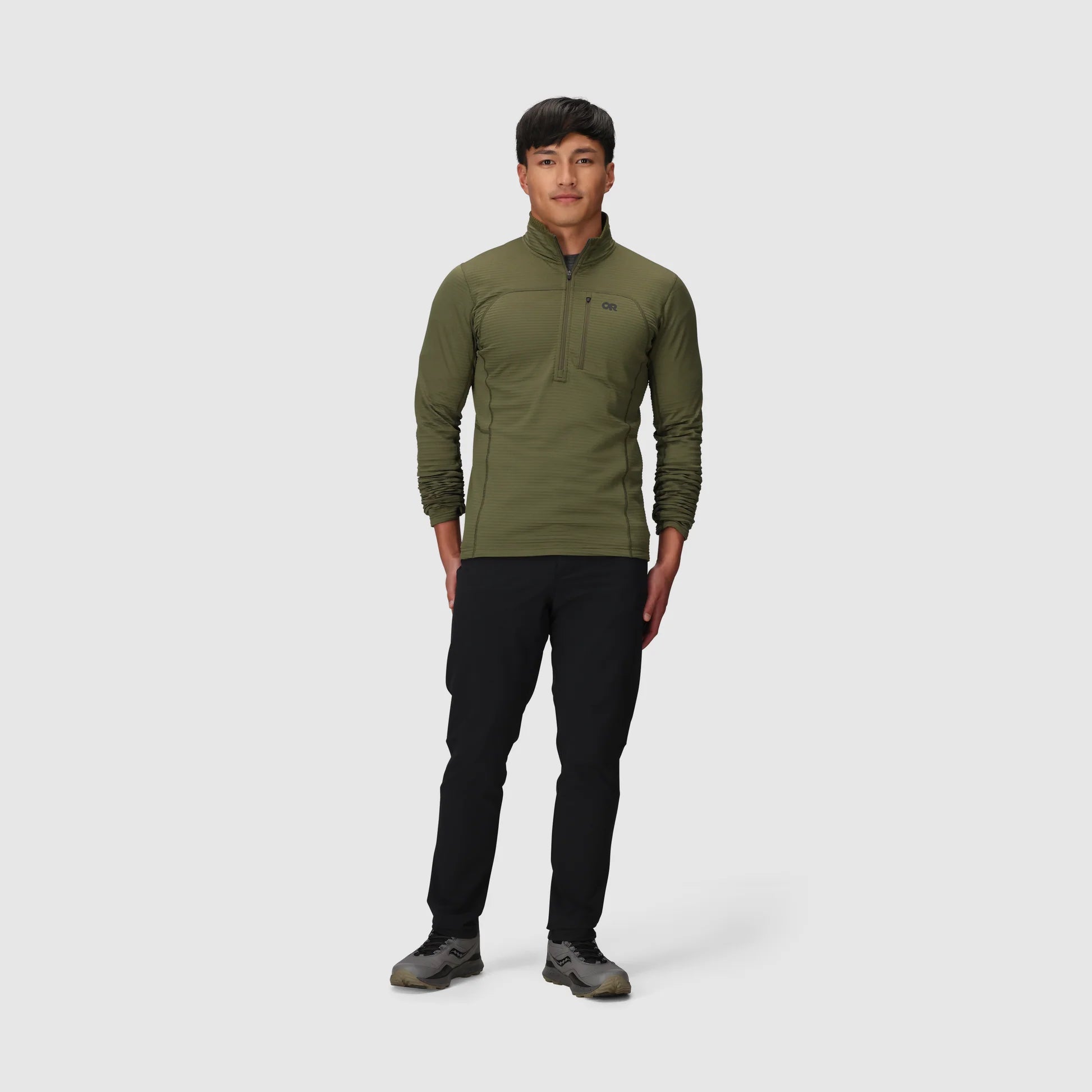 Person wearing a green pullover and black pants on a white background