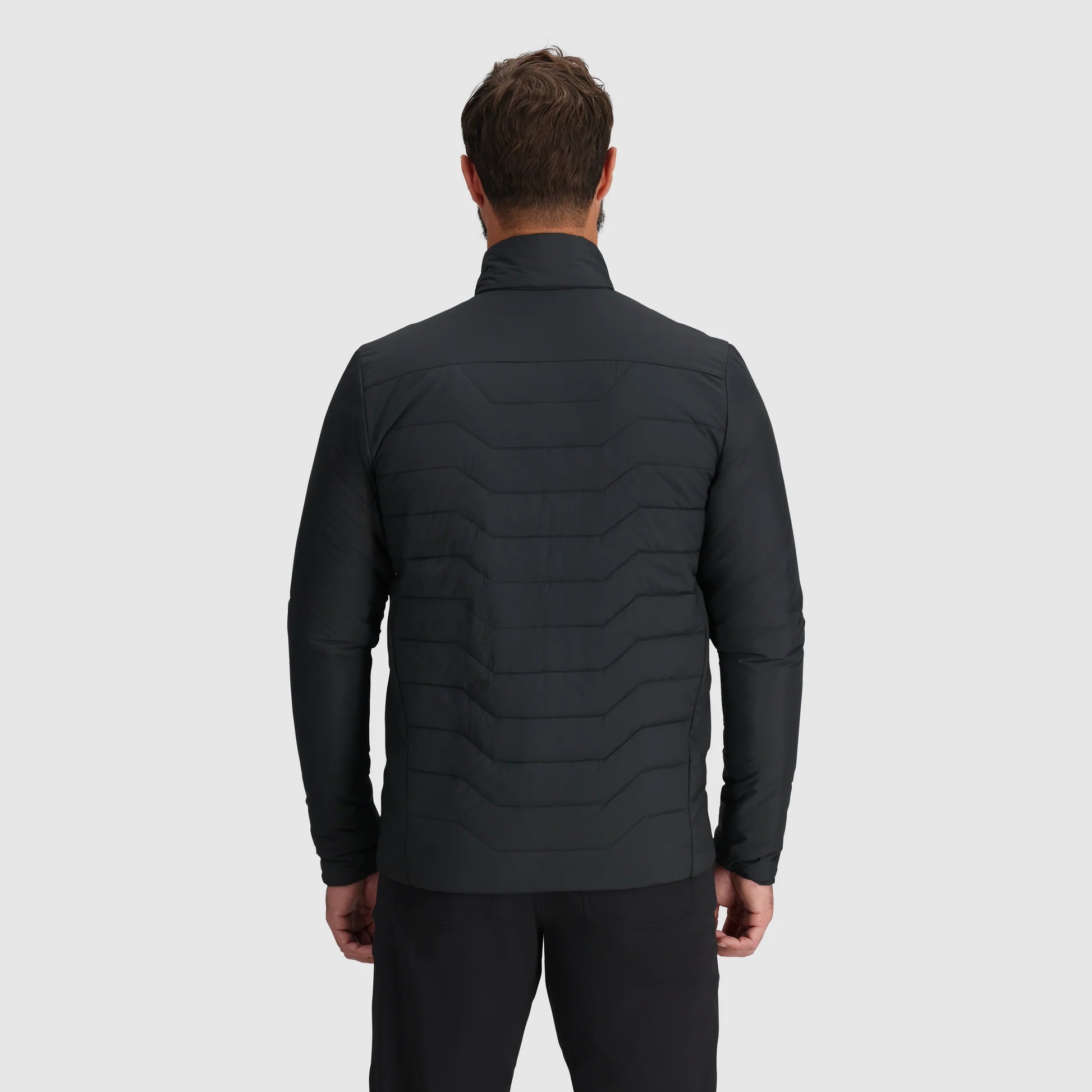 Man wearing a black quilted jacket on a light gray background