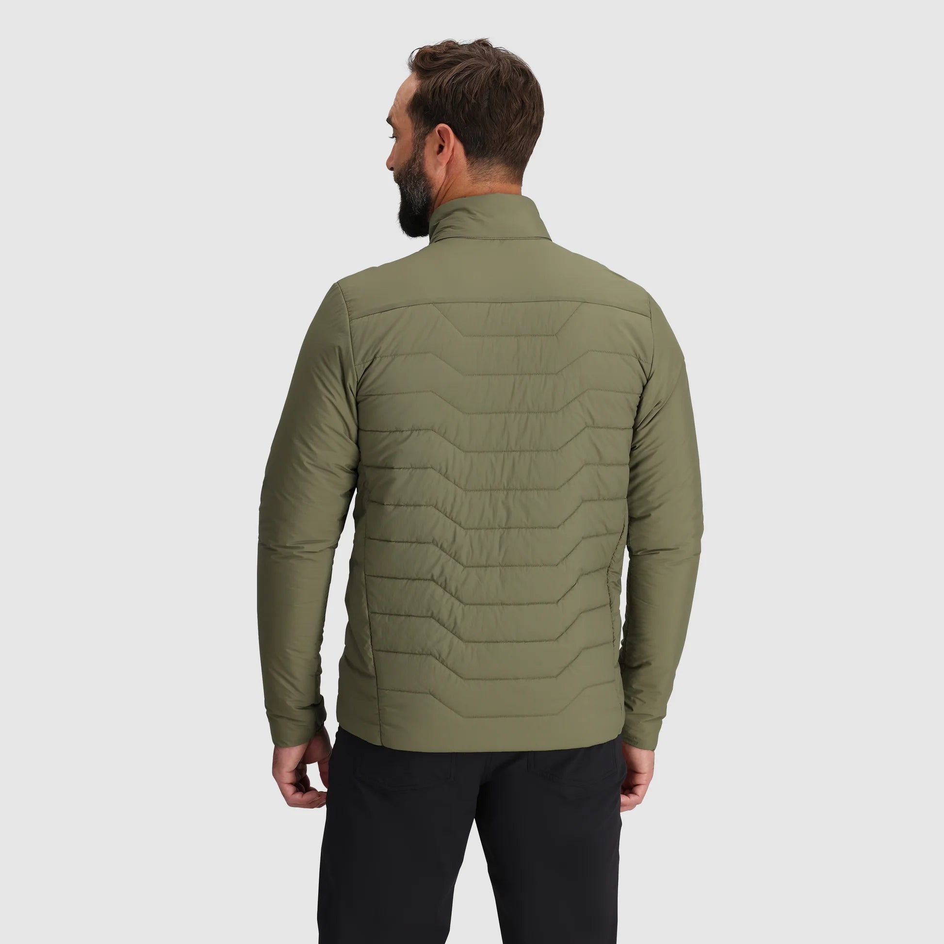 Man wearing a green quilted jacket on a light gray background