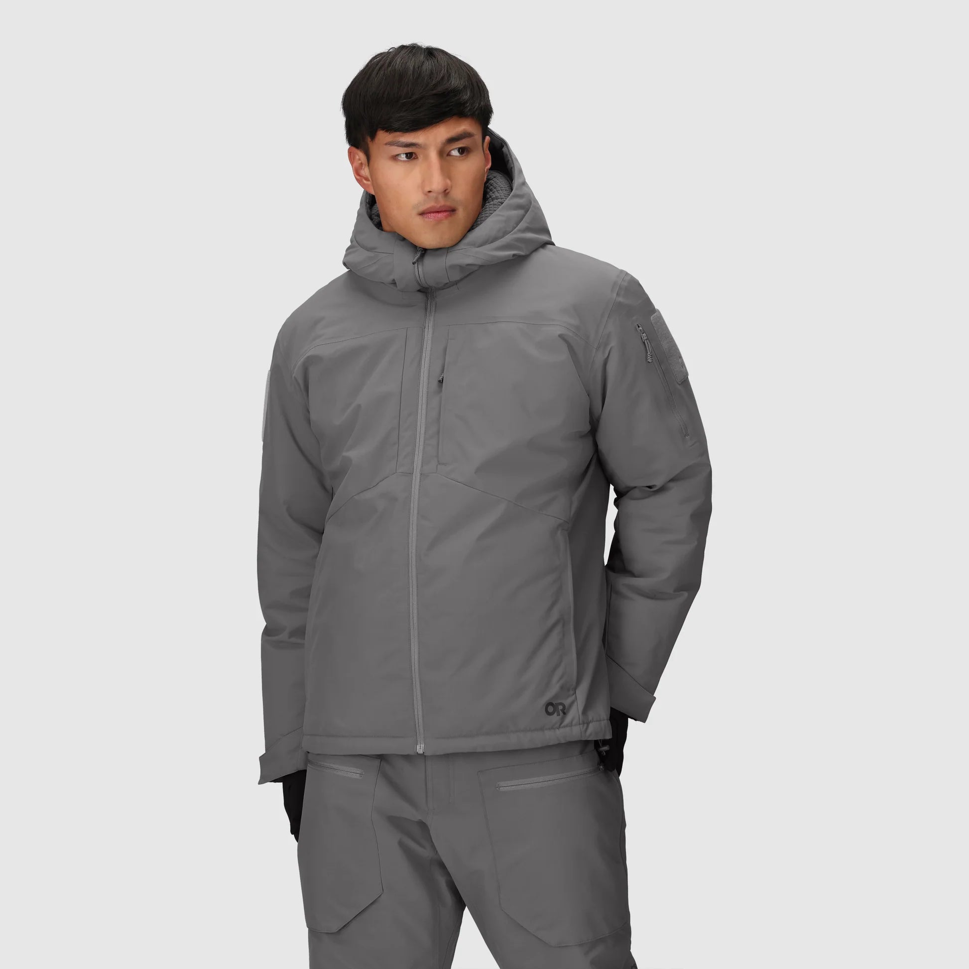 Person wearing a gray jacket and pants on a light gray background