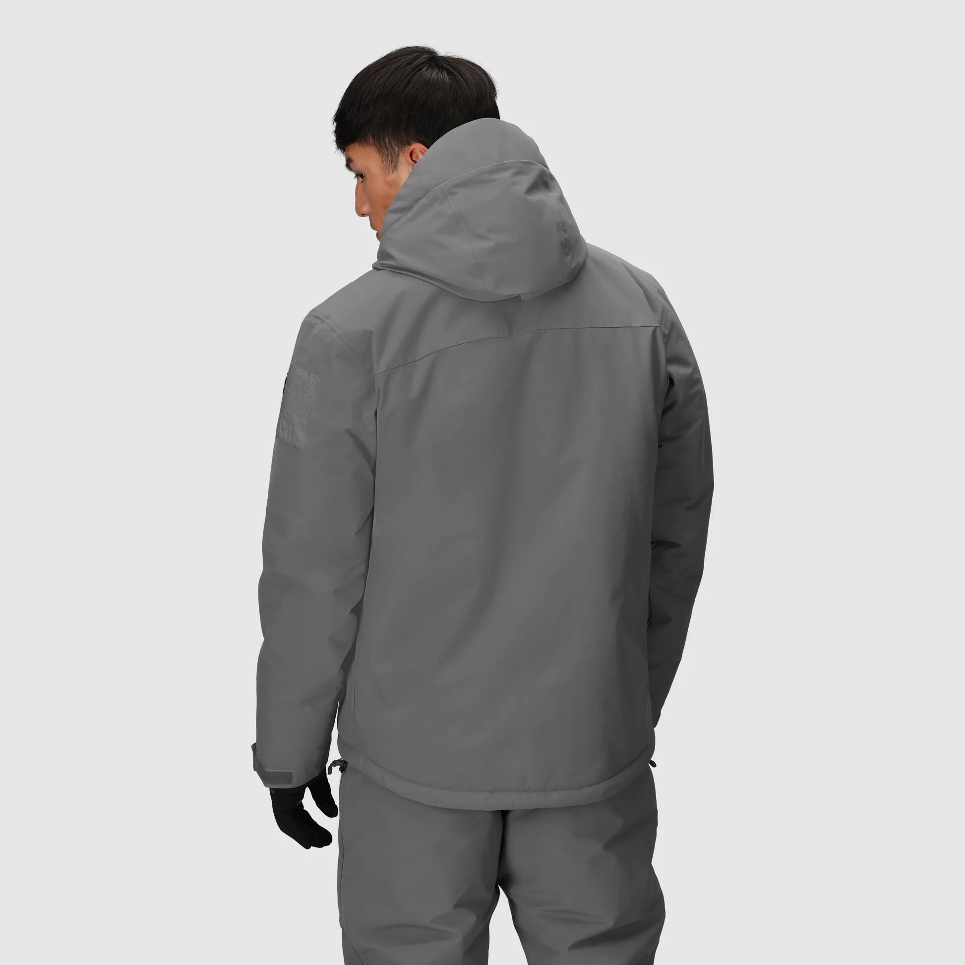 Person wearing a gray jacket and pants on a light gray background