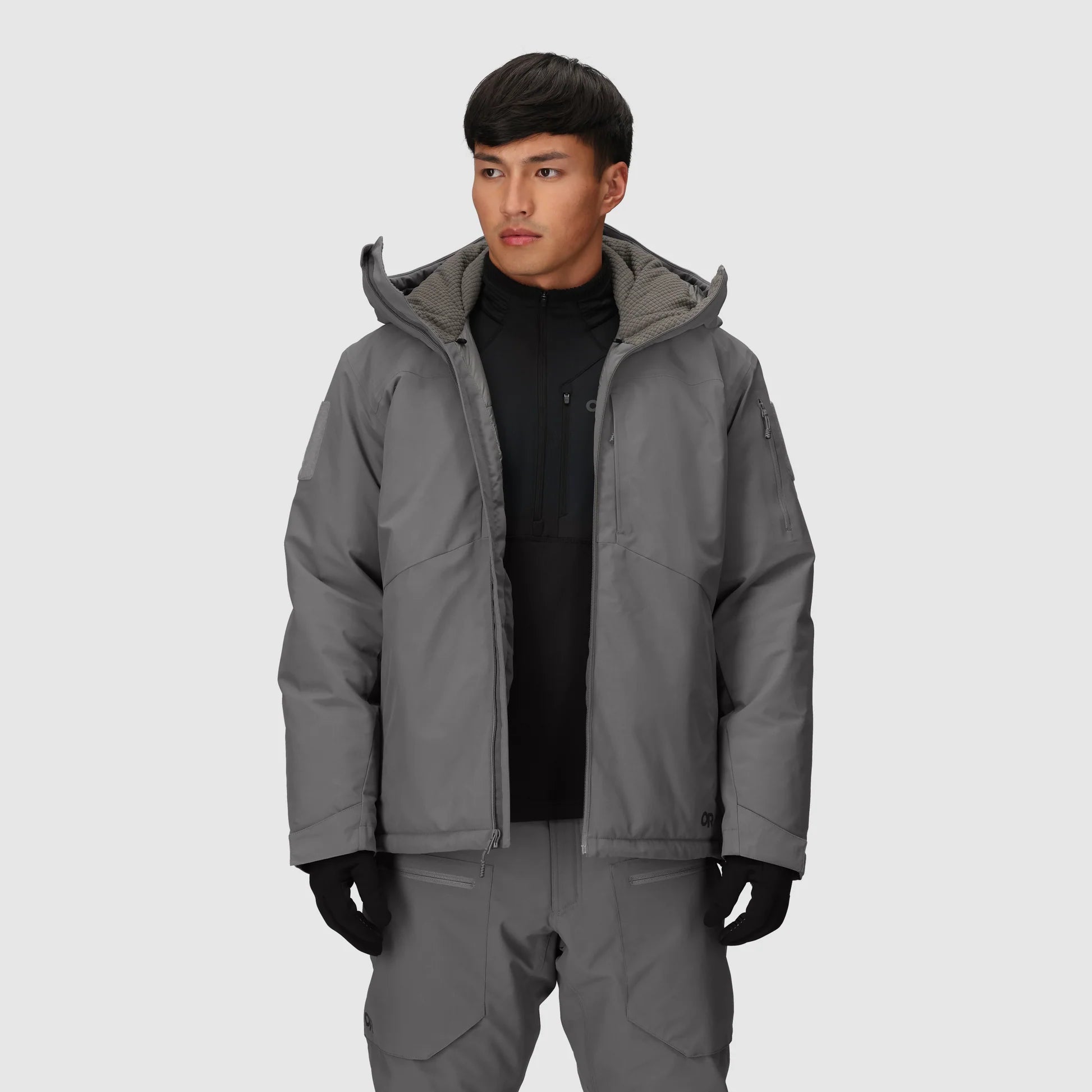 Person wearing a gray jacket and pants on a light gray background