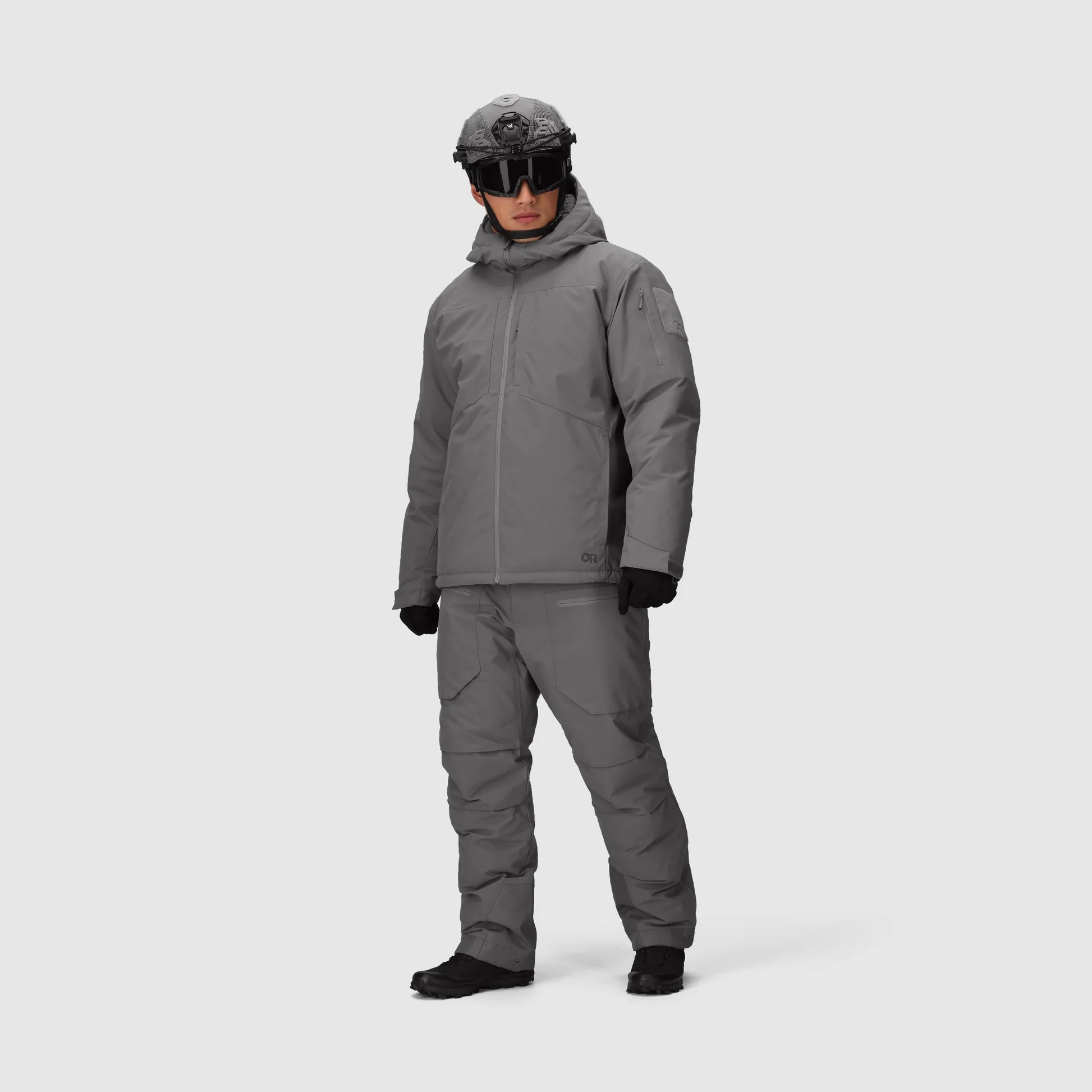 Person wearing a gray snowsuit and helmet on a white background