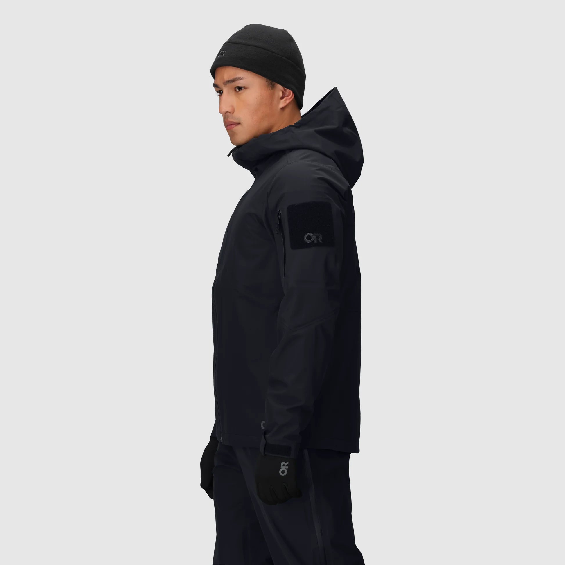 Person wearing a black jacket with a brand logo on a light gray background