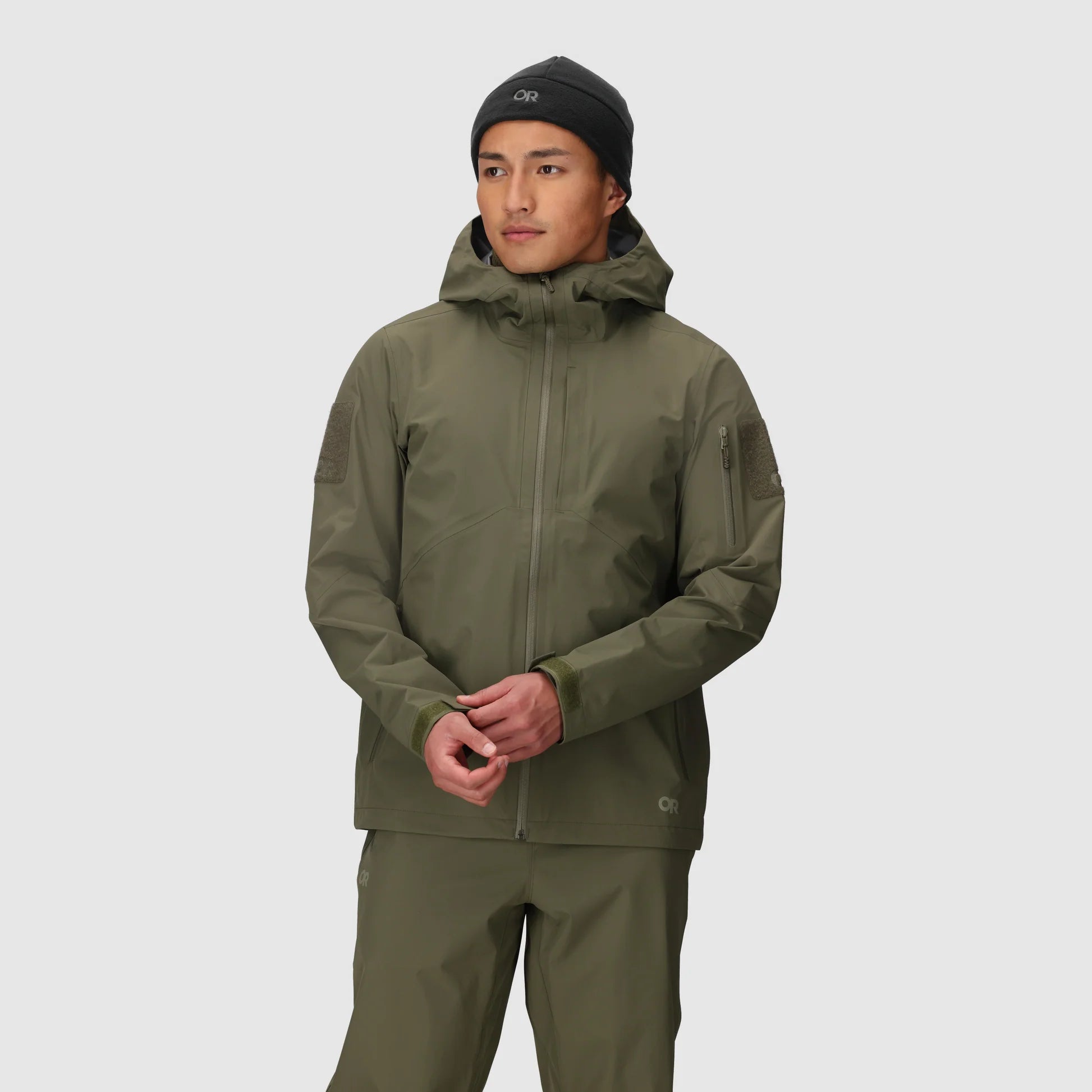 Person wearing a green jacket and pants on a light gray background