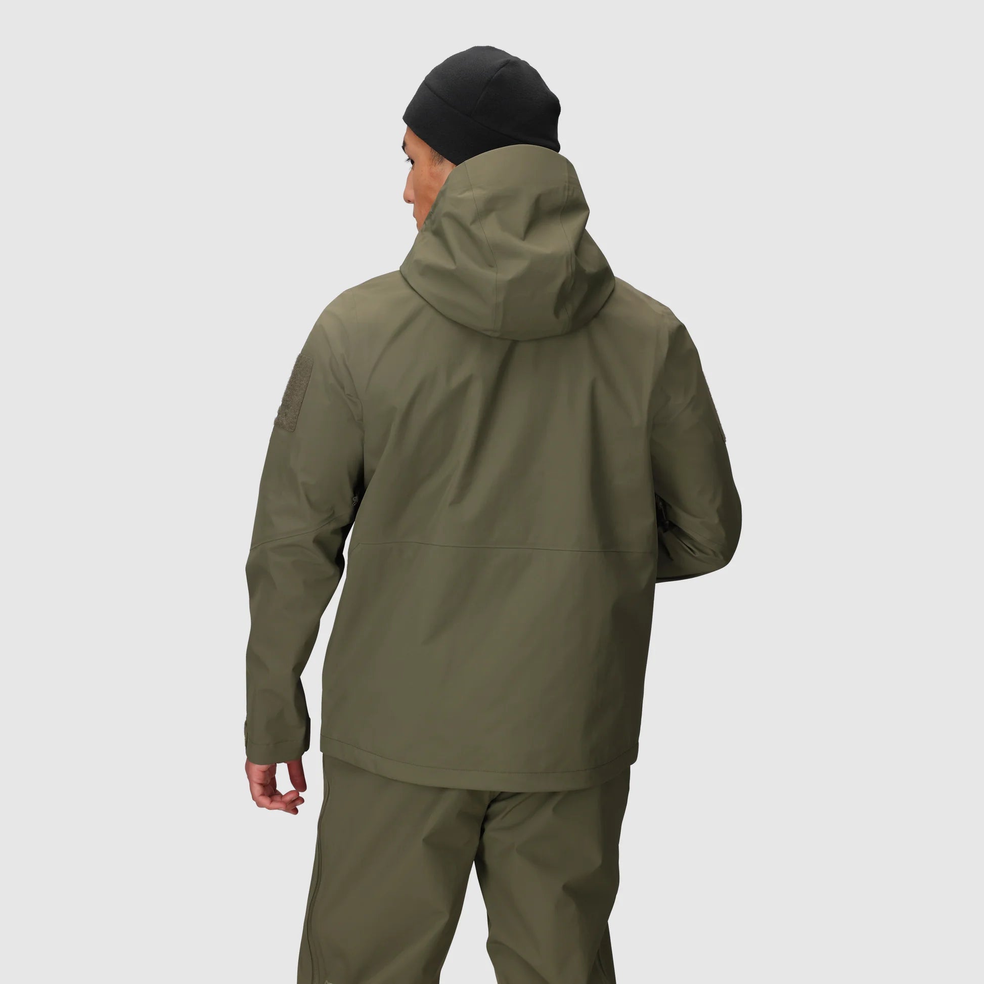 Person wearing a green raincoat and pants on a light gray background