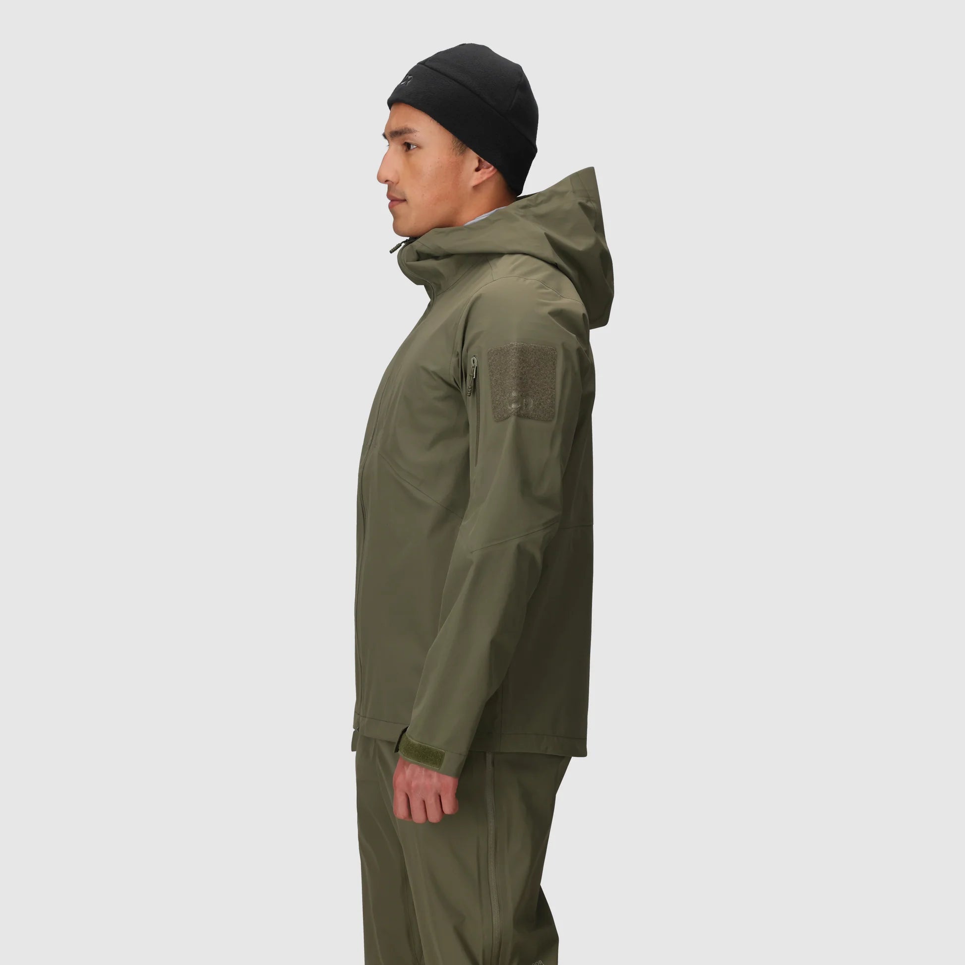 Person wearing a green raincoat and pants on a white background