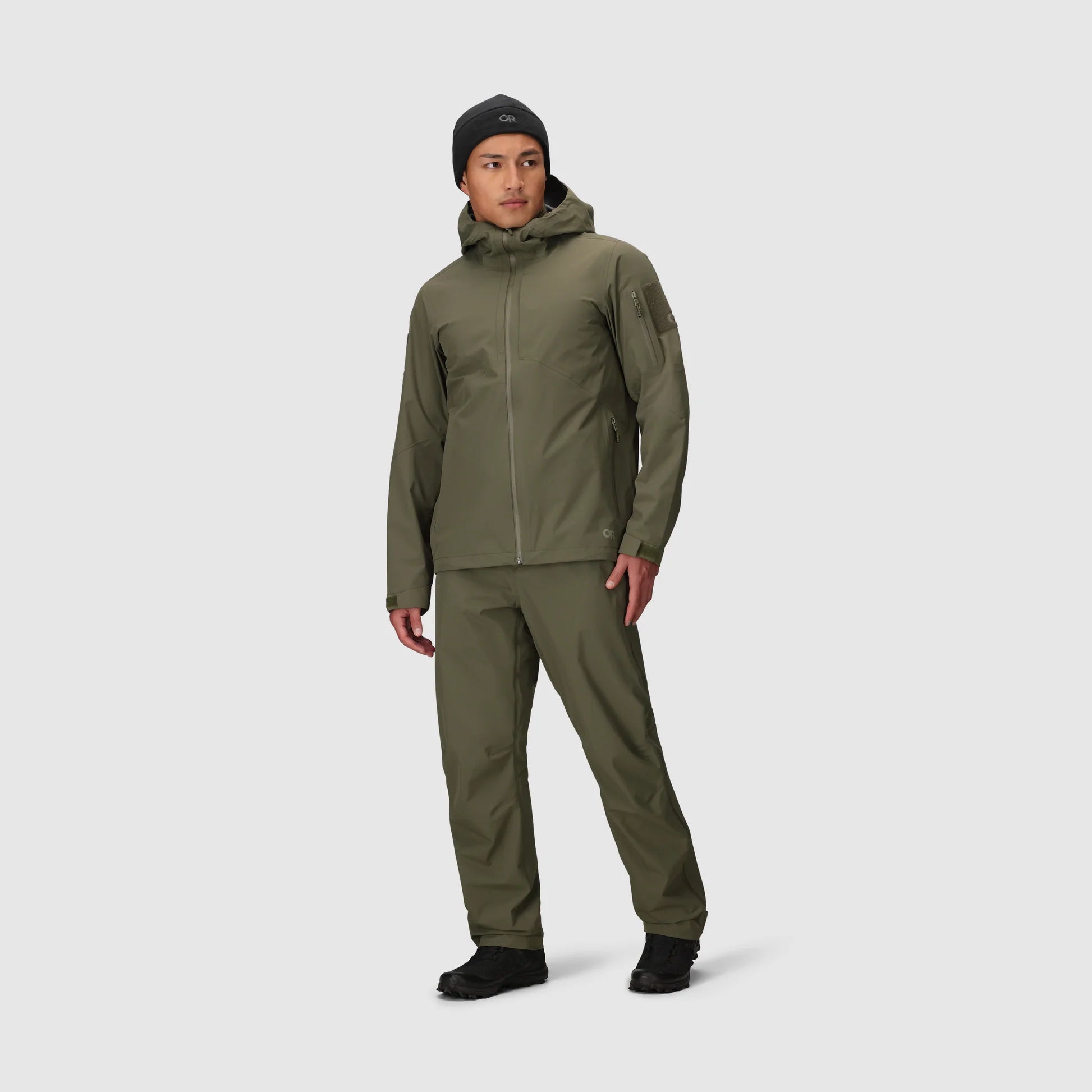 Person wearing a green raincoat and pants on a white background