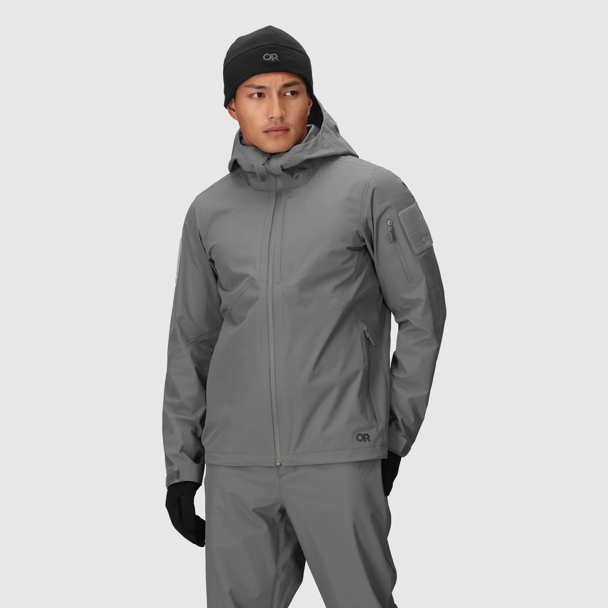 Person wearing a gray raincoat and pants on a light gray background