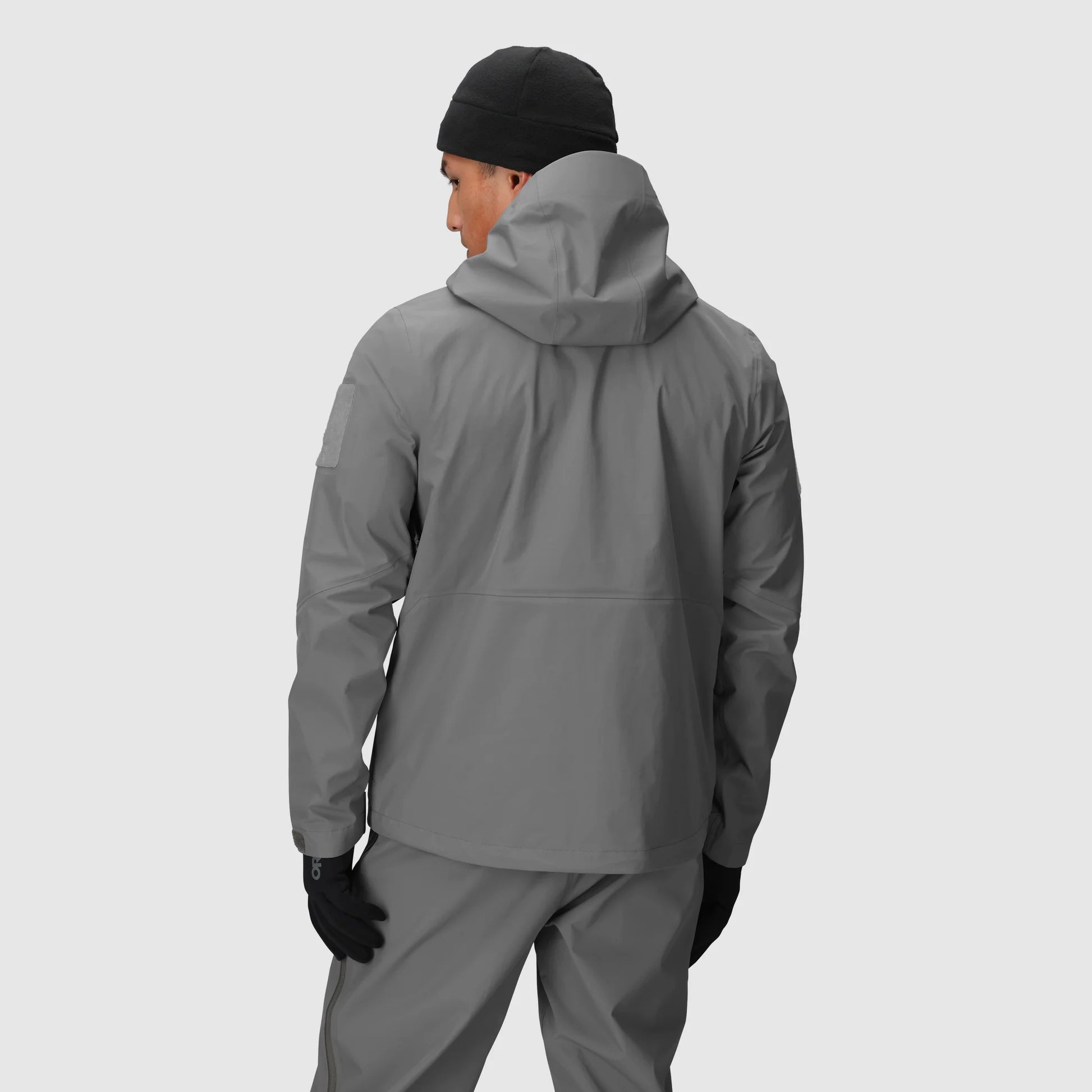 Person wearing a gray raincoat and pants on a light gray background