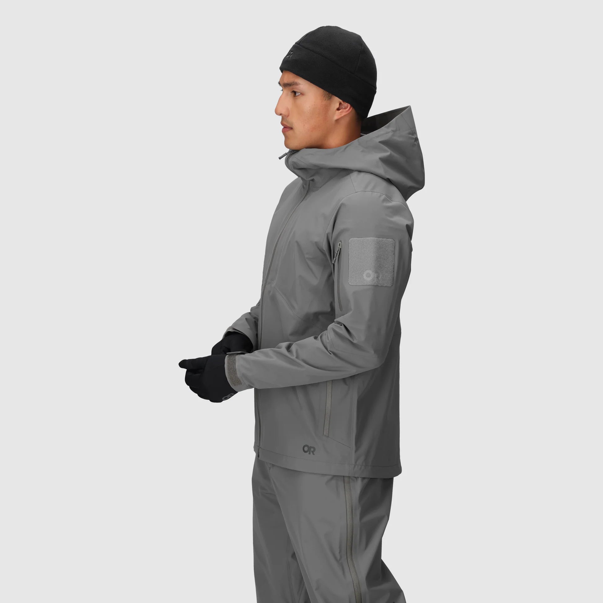 Person wearing a gray raincoat and pants on a white background
