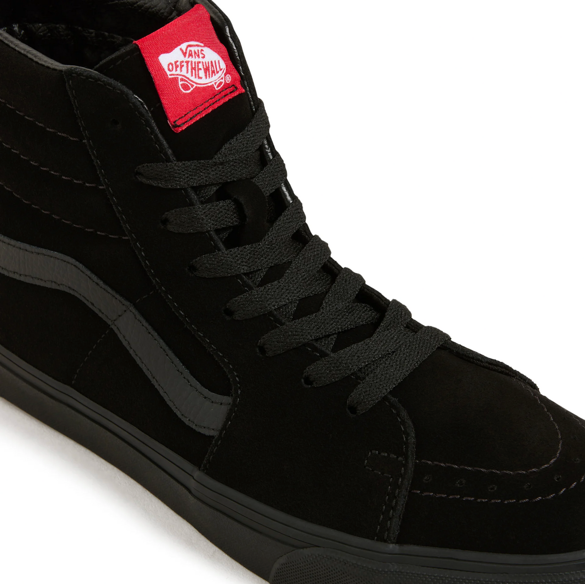 A close-up of a black high-top Vans sneaker, showing the side panel, black laces, and a red Vans 'Off The Wall' tongue label on a white background.