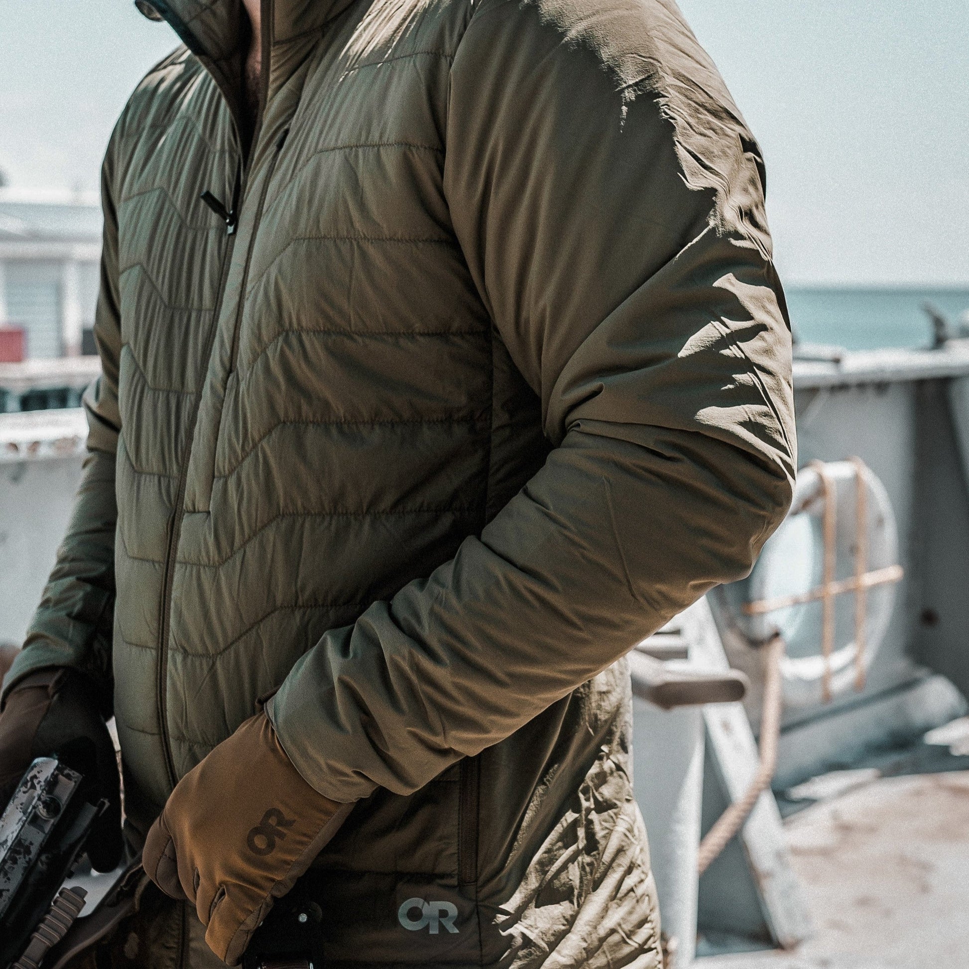 Person wearing a green puffer jacket with a brand logo, standing on a boat.